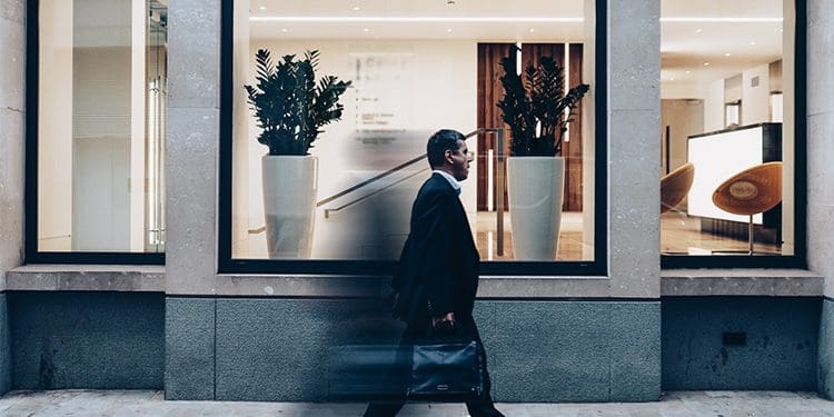 business man walking past a shop window