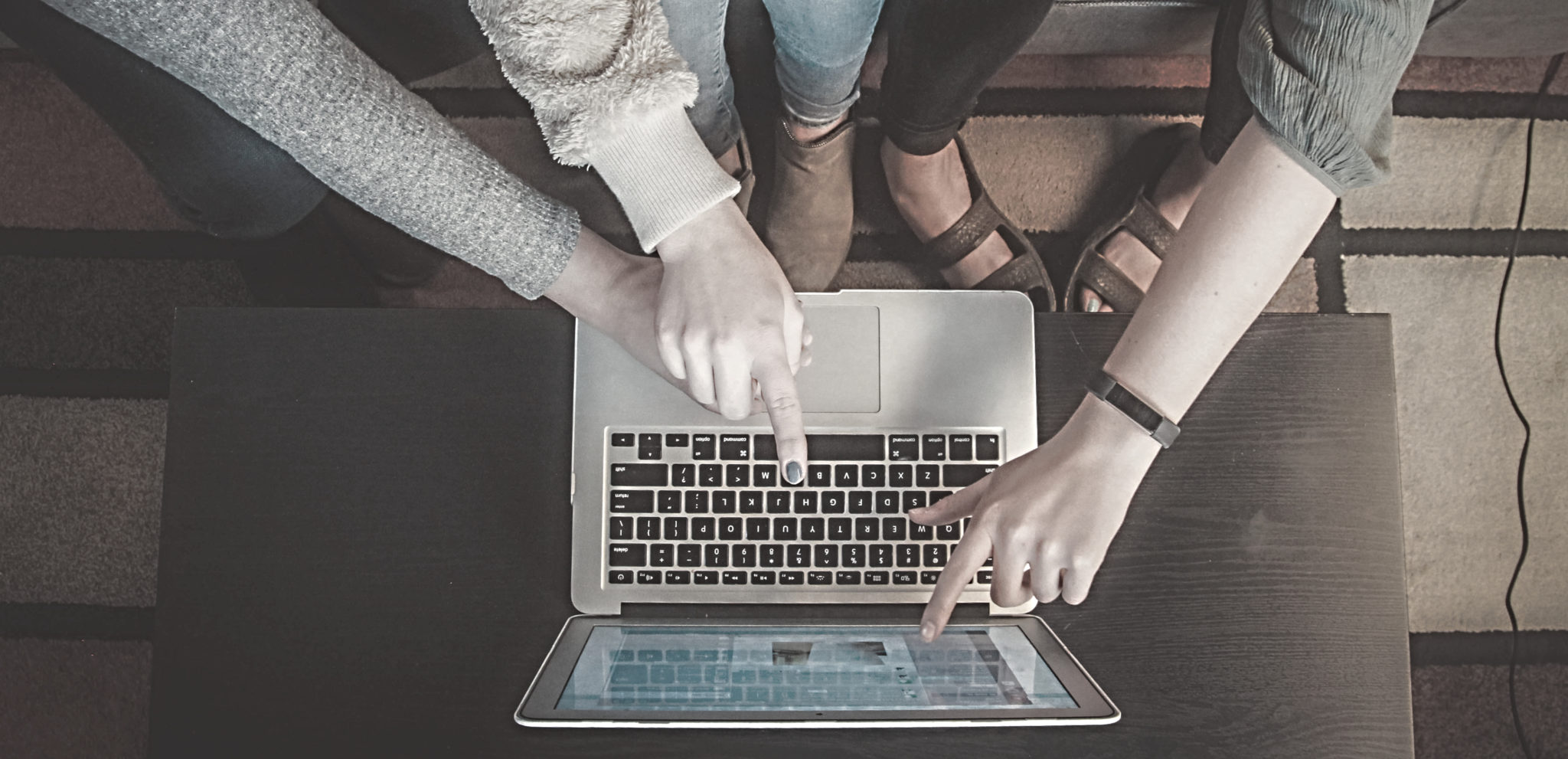 three people looking at the same laptop