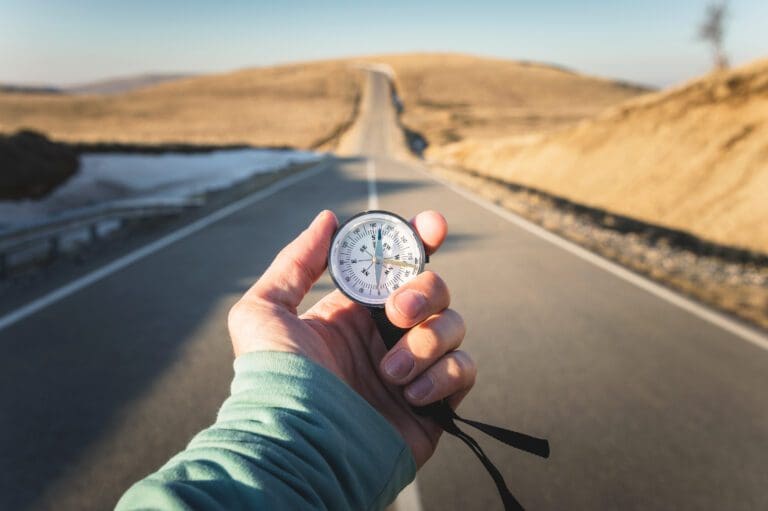hand holding a compass on an empty road